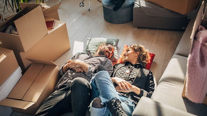 Ein junges Paar freut sich über Ihr neues Zuhause dank Immobilienfinanzierung. 