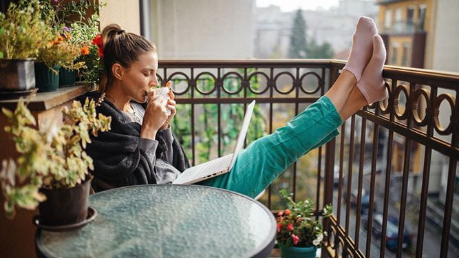 Eine Frau auf dem Balkon beim morgendlichen Kaffee kann sich entspannen, weil sie ihr Vermögen mit einem Vermögensverwaltungsmandat verwalten lässt.