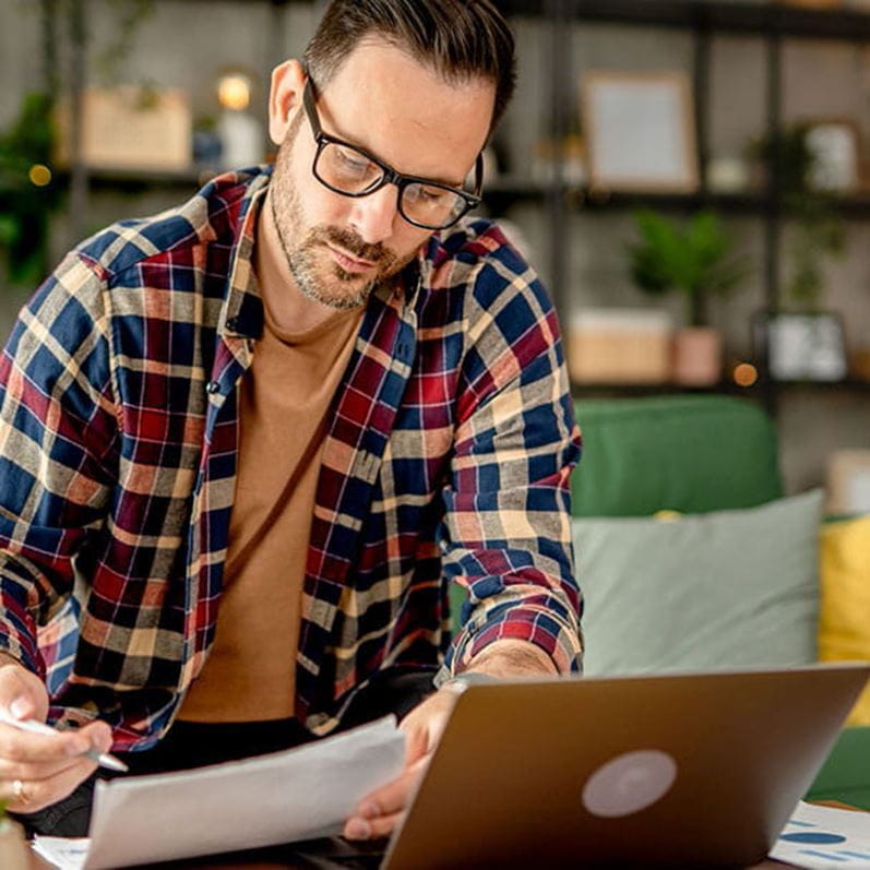 Ein Mann schaut am Laptop nach, ob er genug Eigenmittel für eine Finanzierung mit Hypothek hat.