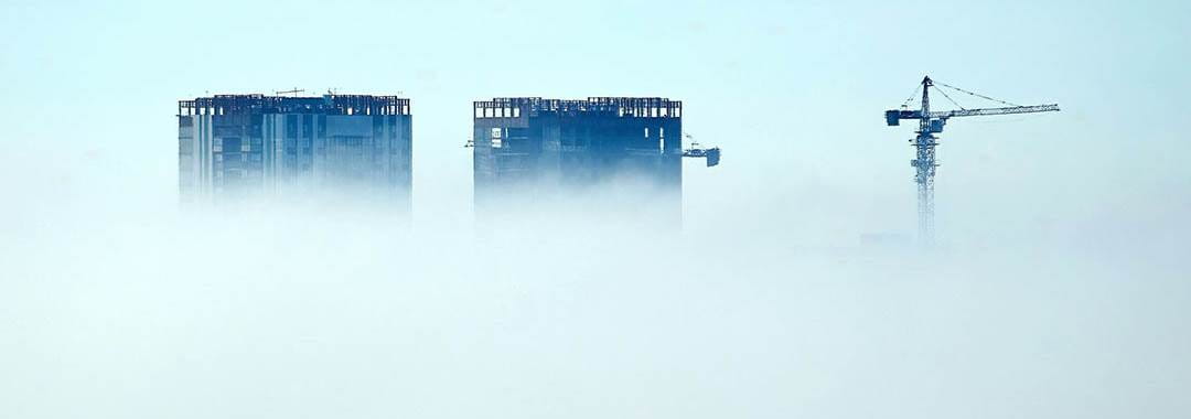 Grattacieli in costruzione e gru superano la coltre di nubi