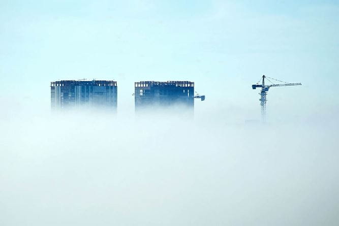 Grattacieli in costruzione e gru superano la coltre di nubi