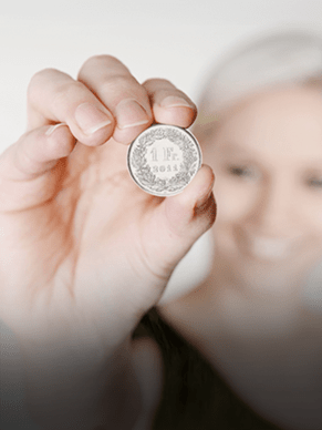 Una donna tiene una moneta da 1 CHF controluce. Infatti, la Soluzione d'investimento è disponibile già a partire da un capitale iniziale di 1 CHF.